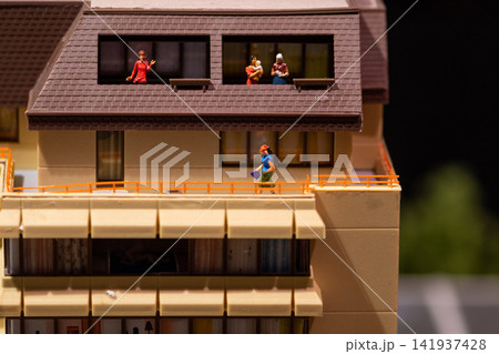 Miniature residential building model with tiny figures on balconies and walkway Miniature residential building model with tiny figures on balconies and walkway 141937428