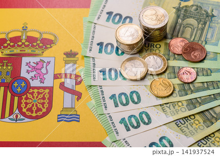 Spain, Spanish euro cash and cent coins against the background of the flag. Euro cash Spain, Spanish euro cash and cent coins against the background of the flag. Euro cash 141937524