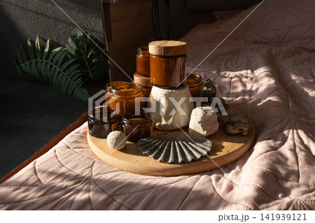 Candle Amber Jars with Wooden Lids on Bed. Candles Glass Jars and Bottles with Natural Elements 141939121