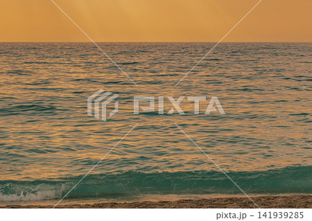 Close up of turquoise sea wave breaking on pebbly Kathisma beach shore under warm golden sunset light Lefkada island Greece travel nature landscape stock photo Close up of turquoise sea wave breaking on pebbly Kathisma beach shore under warm golden sunset light Lefkada island Greece travel nature landscape stock photo 141939285