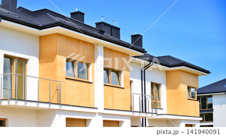New single family houses in a new development area. Residential homes with modern facade. The real estate market in the suburbs. Terraced family homes in newly developed housing estate. New single family houses in a new development area. Residential homes with modern facade. The real estate market in the suburbs. Terraced family homes in newly developed housing estate. 141940091