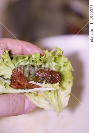 Hand Holding Fresh Lettuce Wrap with Grilled Meat 141940578