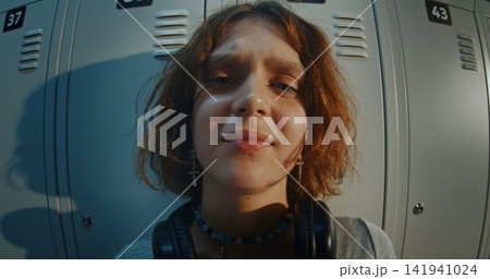 Teenage Girl With Curly Brown Hair Standing in Front of Metal Lockers Teenage Girl With Curly Brown Hair Standing in Front of Metal Lockers 141941024