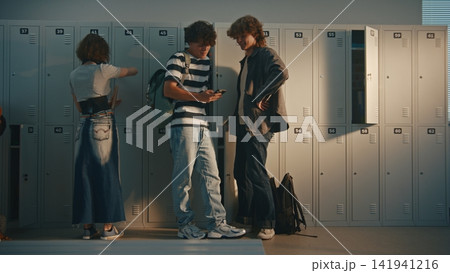 Teenagers Chatting, Sharing Thoughts and Interacting in School Corridor by Lockers 141941216