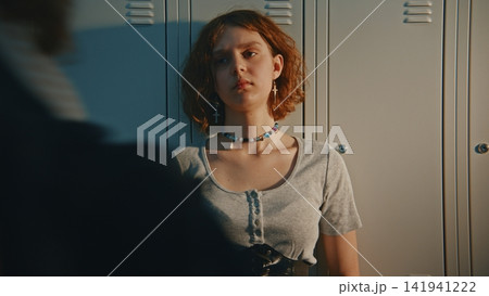 Lonely Teenage Girl Standing by Lockers in Crowded School Corridor Lonely Teenage Girl Standing by Lockers in Crowded School Corridor 141941222