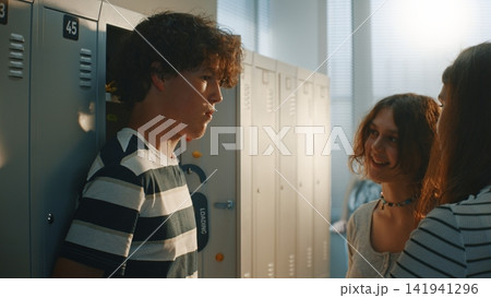 Two Teenage Girls Laughing and Mocking Male Classmate at School Two Teenage Girls Laughing and Mocking Male Classmate at School 141941296