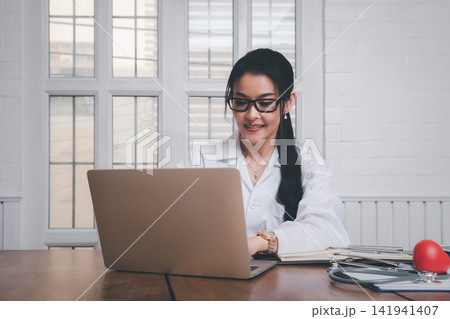 Female doctor working with laptop at office desk in the hospital. Concept of health care and medical. Female doctor working with laptop at office desk in the hospital. Concept of health care and medical. 141941407