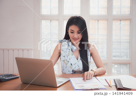 Young asian woman in smart casual wear working with laptop in home office. 141941409