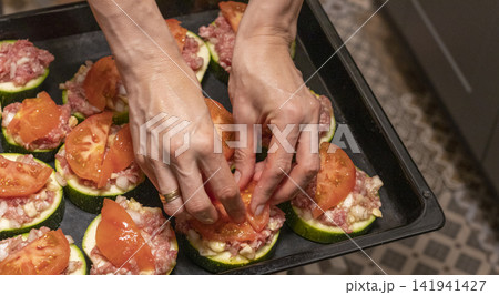 Putting Baking Sheet of Stuffed Zucchini Rounds Inside the Oven Putting Baking Sheet of Stuffed Zucchini Rounds Inside the Oven 141941427