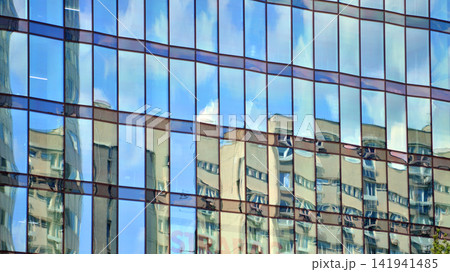 A modern tall building made of steel and glass, housing offices and financial institutions. Glass wall on the facade of the building. A modern tall building made of steel and glass, housing offices and financial institutions. Glass wall on the facade of the building. 141941485