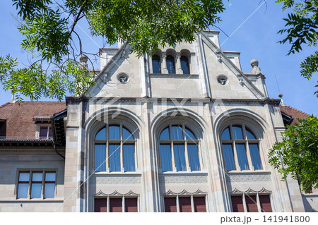 Swiss National Museum Stone Building Facade and Arched Windows View through Tree Leaves in Zurich Swiss National Museum Stone Building Facade and Arched Windows View through Tree Leaves in Zurich 141941800