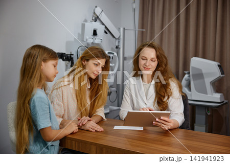Child and mother undergo eye examination together. Pediatric eye screening conducted Child and mother undergo eye examination together. Pediatric eye screening conducted 141941923