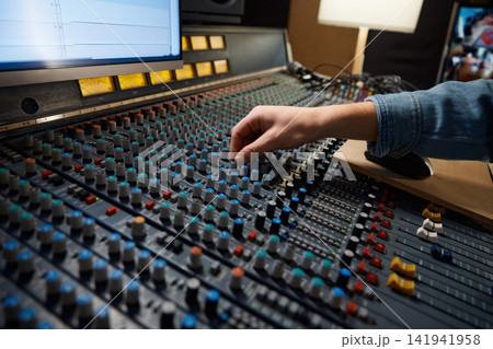 Detailed view of operators manipulating analog mixing knobs during session Detailed view of operators manipulating analog mixing knobs during session 141941958