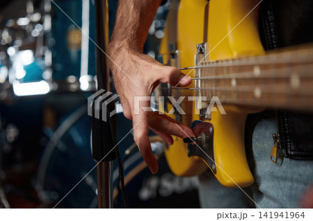 Focused musician manipulating bass string tension close up with textured fret wear visible Focused musician manipulating bass string tension close up with textured fret wear visible 141941964
