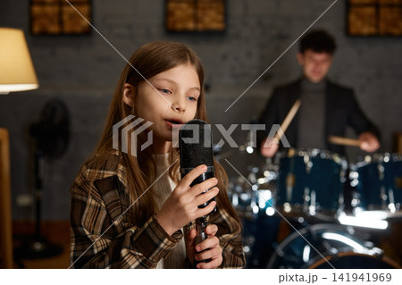 Caucasian girl singing into vintage microphone with dynamic band cooperation Caucasian girl singing into vintage microphone with dynamic band cooperation 141941969