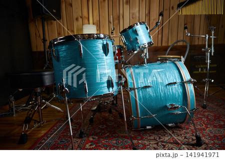 Turquoise drum kit on patterned rug inside warm wooden rehearsal room Turquoise drum kit on patterned rug inside warm wooden rehearsal room 141941971