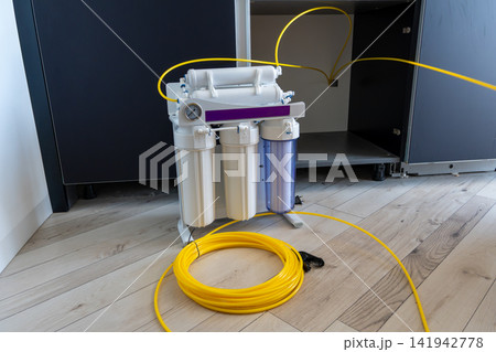 Water purification system with yellow tubes near kitchen cabinet Water purification system with yellow tubes near kitchen cabinet 141942778