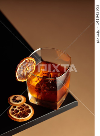 Old-fashioned cocktail with ice and a dried orange slice. 141942958
