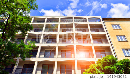 Modern residential building with new apartments in a green residential area. Eco architecture. Green tree and new apartment building. The harmony of nature and modernity. Modern residential building with new apartments in a green residential area. Eco architecture. Green tree and new apartment building. The harmony of nature and modernity. 141943081