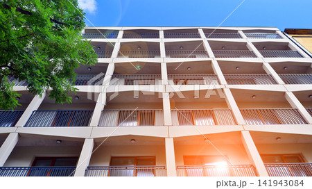 Modern residential building with new apartments in a green residential area. Eco architecture. Green tree and new apartment building. The harmony of nature and modernity. Modern residential building with new apartments in a green residential area. Eco architecture. Green tree and new apartment building. The harmony of nature and modernity. 141943084