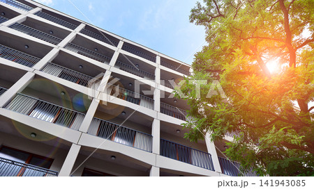 Modern residential building with new apartments in a green residential area. Eco architecture. Green tree and new apartment building. The harmony of nature and modernity. Modern residential building with new apartments in a green residential area. Eco architecture. Green tree and new apartment building. The harmony of nature and modernity. 141943085