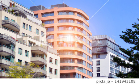 Modern residential building with new apartments in a green residential area. Eco architecture. Green tree and new apartment building. The harmony of nature and modernity. Modern residential building with new apartments in a green residential area. Eco architecture. Green tree and new apartment building. The harmony of nature and modernity. 141943109