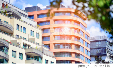 Modern residential building with new apartments in a green residential area. Eco architecture. Green tree and new apartment building. The harmony of nature and modernity. Modern residential building with new apartments in a green residential area. Eco architecture. Green tree and new apartment building. The harmony of nature and modernity. 141943110