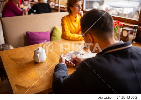 A man holds a white napkin with handwritten phone number text A man holds a white napkin with handwritten phone number text 141943652