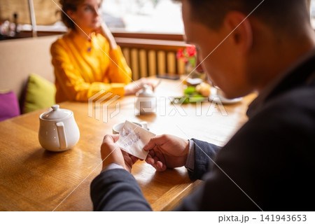 Blurred view of a man looking at a paper napkin note Blurred view of a man looking at a paper napkin note 141943653