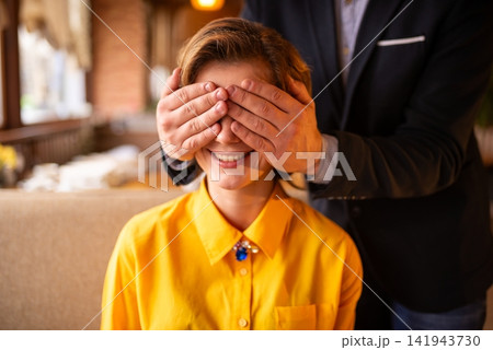 Man covering woman's eyes at a restaurant table Man covering woman's eyes at a restaurant table 141943730