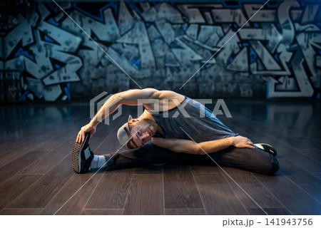 Bearded breakdancer in baseball cap doing wide leg stretch Bearded breakdancer in baseball cap doing wide leg stretch 141943756