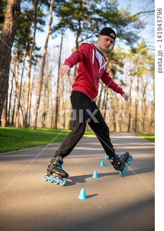 Lower body view of a skater rolling around blue cones on a path Lower body view of a skater rolling around blue cones on a path 141943796