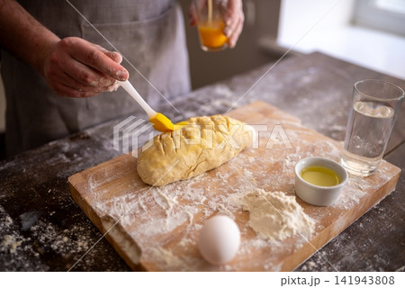 Brushing egg wash onto scored dough before baking 141943808