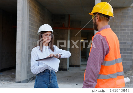 Engineers discussing construction plan on site wearing protective gear Engineers discussing construction plan on site wearing protective gear 141943942