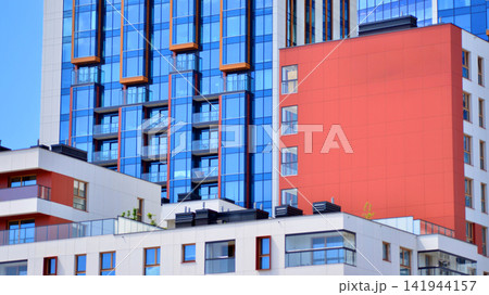 A low-rise residential building stands against a backdrop of tall glass buildings. An urban quarter of modern architecture. 141944157