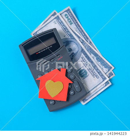 A paper house with golden heart symbol on calculate. A paper house with golden heart symbol on calculate. 141944223