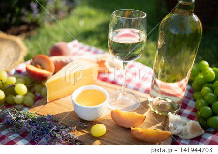 Summer picnic with white wine cheese grapes and peaches outdoors Summer picnic with white wine cheese grapes and peaches outdoors 141944703