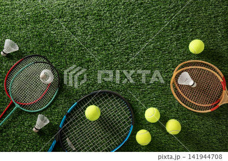 Tennis and badminton rackets with balls on green grass 141944708