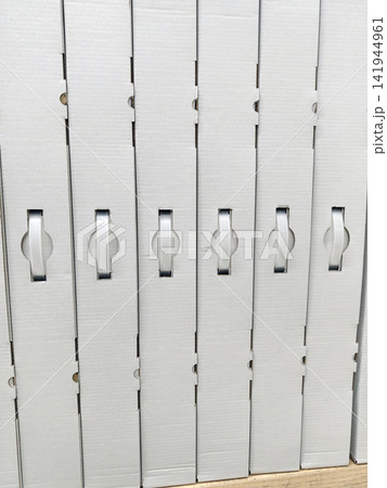 Uniform white cardboard boxes with handles stacked neatly on electronics store shelves showing organized retail packaging of consumer products in modern store environment Uniform white cardboard boxes with handles stacked neatly on electronics store shelves showing organized retail packaging of consumer products in modern store environment 141944961