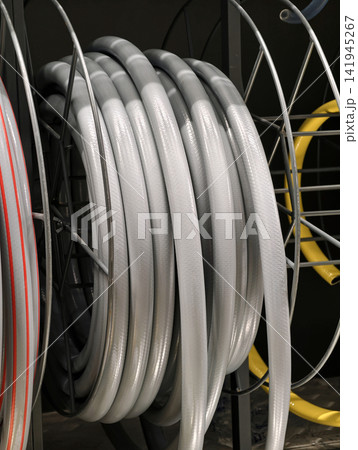 Gray hose rolled into a compact coil is presented in a retail hardware store for general water and utility use Gray hose rolled into a compact coil is presented in a retail hardware store for general water and utility use 141945267