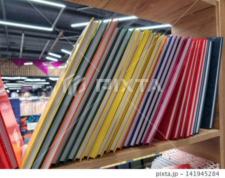 Brightly colored hardbound notebooks arranged in rows on a store shelf, perfect for jotting down notes Brightly colored hardbound notebooks arranged in rows on a store shelf, perfect for jotting down notes 141945284