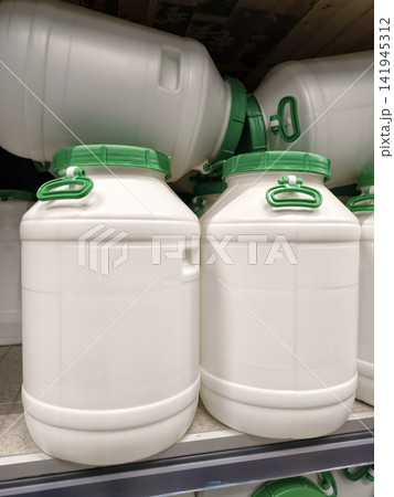 Plastic white barrels with green lids stacked efficiently on shelves inside a hardware store Plastic white barrels with green lids stacked efficiently on shelves inside a hardware store 141945312