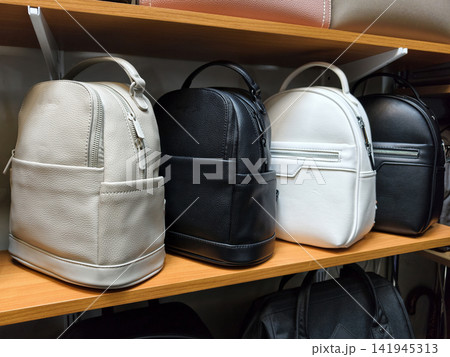 Small leather backpacks in multiple shades are presented on shelves in a store for customers to explore Small leather backpacks in multiple shades are presented on shelves in a store for customers to explore 141945313