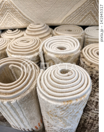 Comfortable textured carpets rolled into large rolls displayed in a superstore with decorative materials and elegant patterns Comfortable textured carpets rolled into large rolls displayed in a superstore with decorative materials and elegant patterns 141945317