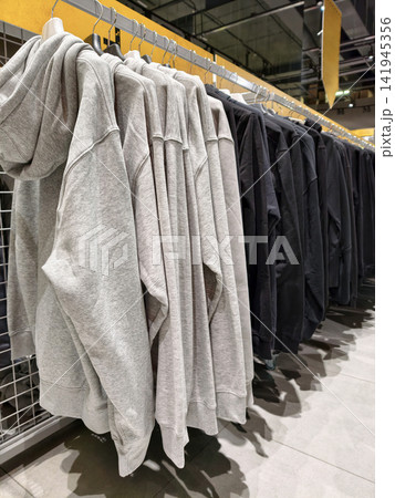 Gray hooded sweatshirts hanging neatly on hangers inside a sporting goods store present a clean and practical selection of comfortable clothing for everyday wear Gray hooded sweatshirts hanging neatly on hangers inside a sporting goods store present a clean and practical selection of comfortable clothing for everyday wear 141945356