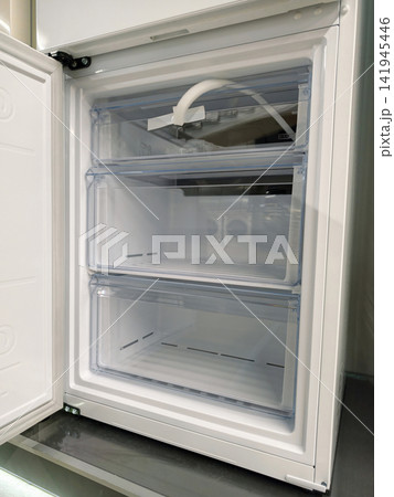 Large white refrigerator lower freezer compartment with open door Large white refrigerator lower freezer compartment with open door 141945446