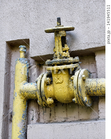Gas pipeline shut off mechanism mounted on residential property exterior with yellow metal pipe, highlighting technical engineering equipment used in utility networks 141945511