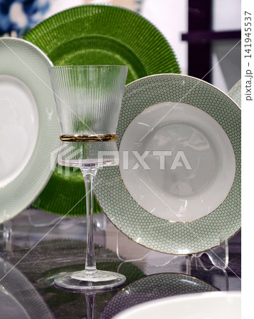 Sophisticated single glass with vivid green plates behind on an upscale dining table Sophisticated single glass with vivid green plates behind on an upscale dining table 141945537