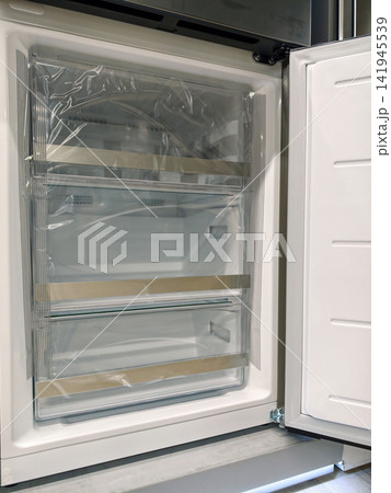 Sleek modern fridge with open freezer door, perfect for stylish kitchens, for sale in a home appliance superstore 141945539