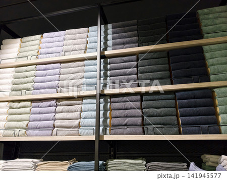 Assorted multicolored towels folded neatly on wide shelves in home supply store Assorted multicolored towels folded neatly on wide shelves in home supply store 141945577